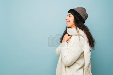 Photo for Gorgeous young woman smiling feeling very happy about the winter season wearing a sweater and knit hat during the cold next to copy space ad - Royalty Free Image