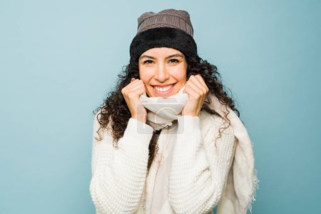 Photo for Gorgeous cheerful young woman with a scarf and knit hat smiling enjoying the cold weather season during winter - Royalty Free Image