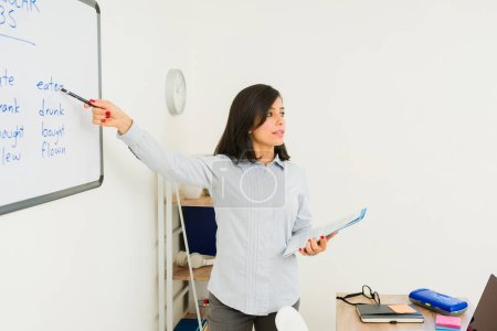 Téléchargez les photos : Femme intelligente enseignant une leçon d'anglais et pointant vers le tableau blanc travaillant dans l'enseignement des langues étrangères - en image libre de droit