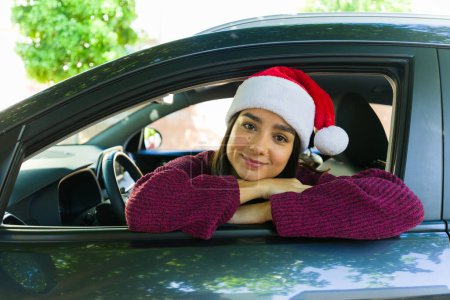 Téléchargez les photos : Mexicaine jolie femme avec un chapeau de Père Noël célébrant les vacances de Noël au volant de sa voiture - en image libre de droit