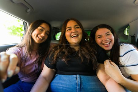 Photo for Excited women friends laughing and having fun in the car while going on a fun trip together looking happy - Royalty Free Image