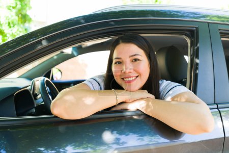 Téléchargez les photos : Belle jeune femme souriant regardant heureux dans la voiture tout en étant prêt à conduire sa voiture se sentant joyeux - en image libre de droit