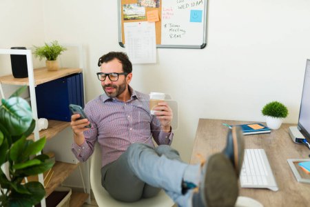 Photo for Relaxed happy caucasian boss and supervisor in the office using glasses and texting on the smartphone smiling while relaxing at work - Royalty Free Image