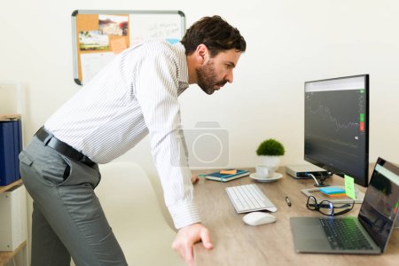 Foto de Atractivo inversor que compra acciones que trabajan en la oficina mientras revisa el mercado de valores en línea en el ordenador - Imagen libre de derechos