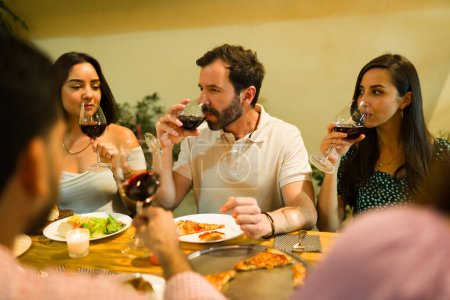 Foto de Atractivo grupo de personas cenando y bebiendo vino para una celebración con amigos que parecen felices - Imagen libre de derechos