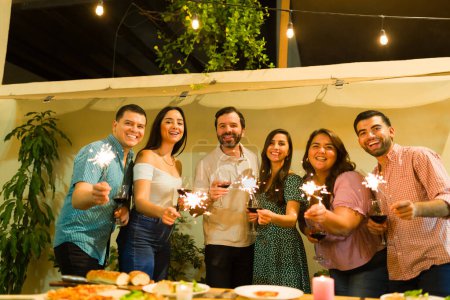 Téléchargez les photos : Groupe excité d'amis heureux souriant et s'amusant à célébrer l'amitié en utilisant des étincelles - en image libre de droit