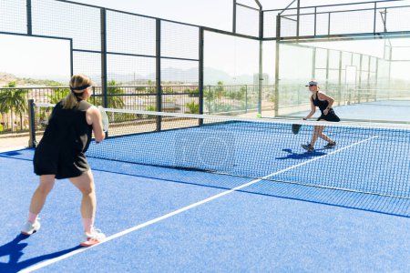 Photo for Sporty women practicing and training padel tennis outdoors while playing a match at the tennis court - Royalty Free Image