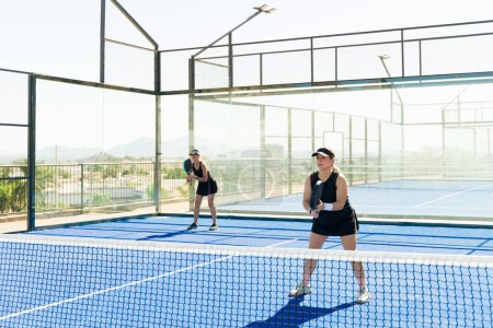 Téléchargez les photos : Équipe féminine active jouissant d'un match de tennis padel avec des amis sur le court de tennis en plein air - en image libre de droit