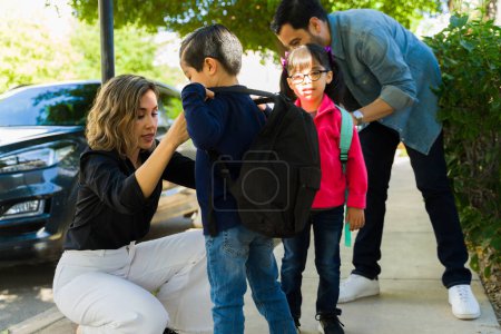 Foto de Hermosa mamá y papá hablando con sus hijos pequeños mientras los dejan en la escuela primaria - Imagen libre de derechos