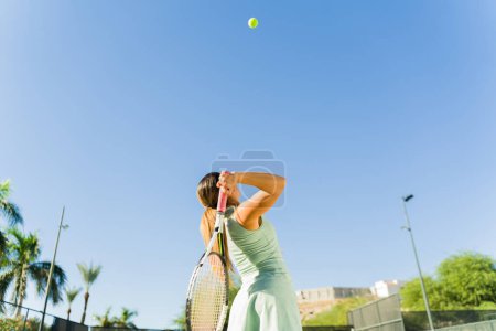 Téléchargez les photos : Sporty belle jeune femme de formation et de pratiquer son tennis servir à l'extérieur pendant une journée ensoleillée - en image libre de droit