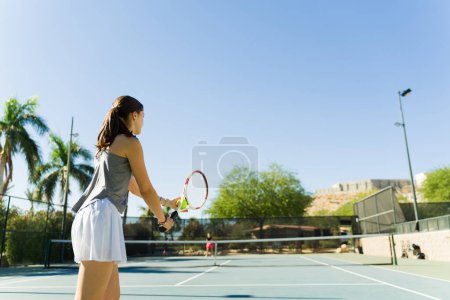 Téléchargez les photos : Actif caucasien adolescent fille jouer un tennis jeu à l'extérieur et avoir amusant pratiquer son tennis servir - en image libre de droit