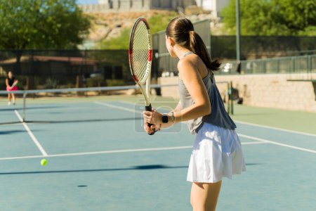 Foto de Hermosa adolescente caucásica chica sosteniendo una raqueta jugando al tenis con un amigo al aire libre en la cancha de tenis - Imagen libre de derechos