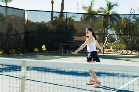 Téléchargez les photos : Caucasienne adolescente active utilisant une raquette jouant à un jeu de tennis et pratiquant son revers - en image libre de droit