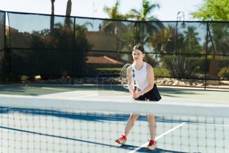 Foto de Deportivo caucásico adolescente chica divirtiéndose al aire libre jugando un juego de tenis durante sus lecciones - Imagen libre de derechos