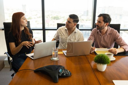 Foto de Equipo de empresarios en ropa casual usando computadoras portátiles y teniendo una discusión en una sala de reuniones - Imagen libre de derechos