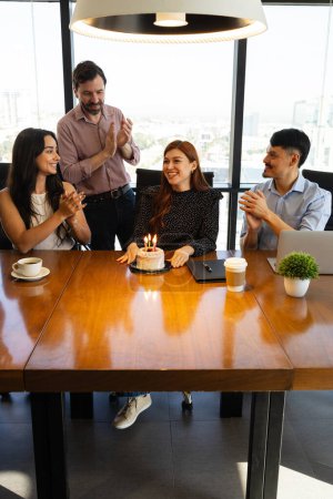 Foto de Hermosa mujer con un pastel de cumpleaños recibiendo una agradable celebración de sus compañeros de trabajo en una oficina - Imagen libre de derechos