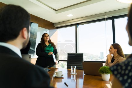 Foto de Retrato de una hermosa mujer de negocios con sobrepeso hablando con un grupo de compañeros de trabajo y dando una presentación de negocios - Imagen libre de derechos