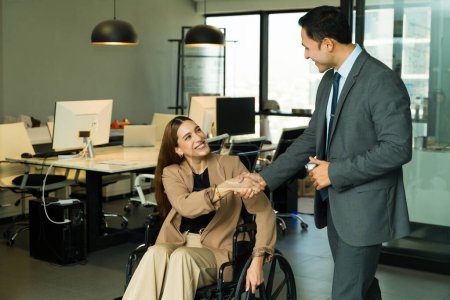 Téléchargez les photos : Femme d'affaires handicapée parler à un collègue et donner une poignée de main dans un bureau inclusif - en image libre de droit