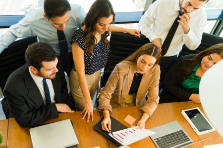 Photo for High angle view of a group of businesspeople looking at some graphs in a meeting - Royalty Free Image