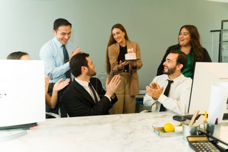 Photo for Excited man receiving the best wishes for his birthday and a cake from a group of colleagues at the office - Royalty Free Image