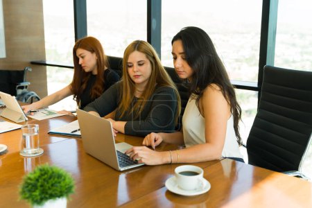 Photo for Diverse group of businesswomen dressed casual and using a laptop computer in a meeting room - Royalty Free Image