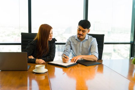 Foto de Atractiva empresaria revisando un contrato con un colega durante una reunión de negocios - Imagen libre de derechos