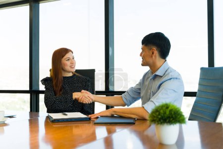 Téléchargez les photos : Poignée de main entre une femme d'affaires et un homme d'affaires après la conclusion d'un accord dans une salle de réunion - en image libre de droit