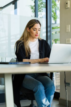 Foto de Hermosa mujer de negocios trabajando en un ordenador portátil mientras está sentada en una sala de reuniones - Imagen libre de derechos