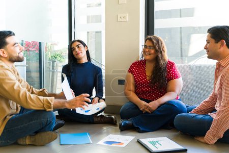 Photo for Happy group of diverse people sitting in the floor while having a casual team meeting - Royalty Free Image