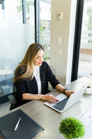 Foto de Mujer de negocios bastante caucásica buscando ocupado mientras se utiliza un ordenador portátil en una sala de reuniones - Imagen libre de derechos