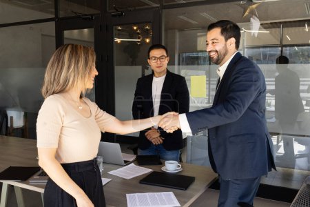 Foto de Feliz hombre de negocios estrechando la mano con una mujer después de cerrar un trato en una oficina - Imagen libre de derechos
