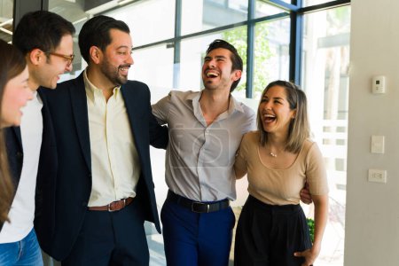 Téléchargez les photos : Groupe de gens d'affaires s'embrassant et riant ensemble dans un bureau - en image libre de droit
