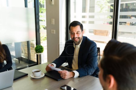 Photo for Hispanic businessman looking happy while having a meeting with his team - Royalty Free Image