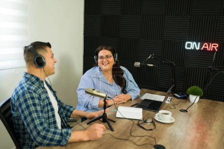 Téléchargez les photos : Femme excitée et animateur à la station de radio parlant en direct avec un invité masculin lors d'un podcast talk-show - en image libre de droit