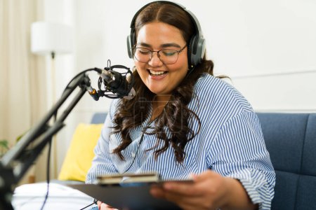 Foto de Mujer emocionada y anfitriona riendo mientras graba un podcast con auriculares y un micrófono durante su episodio de talk show - Imagen libre de derechos