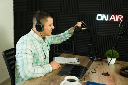 Téléchargez les photos : Homme hispanique joyeux et animateur de podcast à l'antenne au studio pendant son émission de radio amusant souriant - en image libre de droit