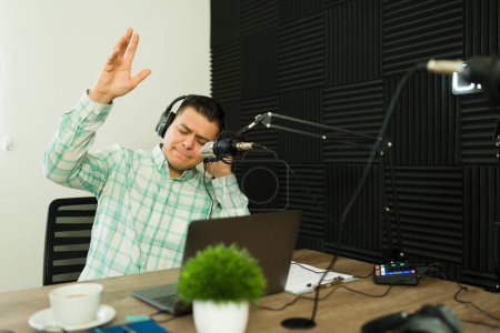 Téléchargez les photos : Homme latin joyeux avec écouteurs appréciant écouter de la musique pendant son émission de radio ou podcast - en image libre de droit