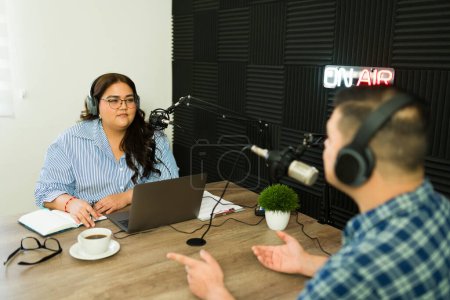 Photo for Woman broadcast and radio host in the recording studio during her talk show with a guest asking questions for an interview on air - Royalty Free Image
