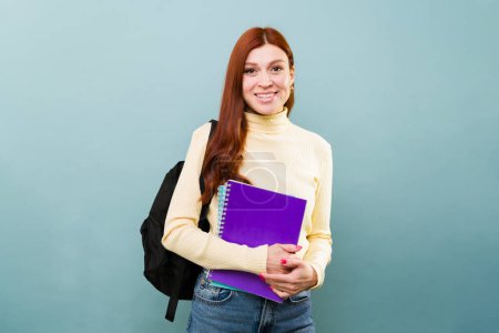 Téléchargez les photos : Portrait d'une jolie étudiante rousse aux cheveux roux souriant allant à l'université avec un sac à dos - en image libre de droit