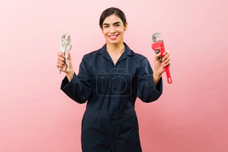 Photo for Cheerful attractive female plumber showing her tools and ready to work on repair looking happy making eye contact - Royalty Free Image