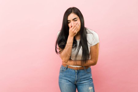 Téléchargez les photos : Jeune femme malade souffrant de nausées voulant vomir à cause de maux d'estomac devant un fond rose - en image libre de droit