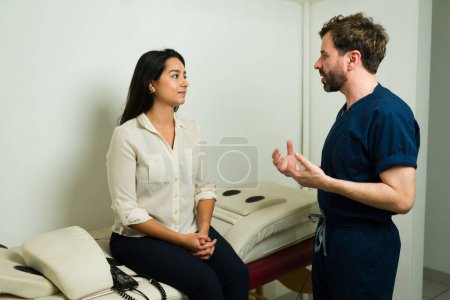 Foto de Terapeuta masculino explicando a una mujer feliz sobre el masaje biofísico alternativo en la clínica de bienestar - Imagen libre de derechos