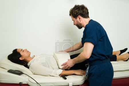 Relaxed woman at the wellness clinic receiving an alternative method and massage vibrations on her abdomen with andullation therapy