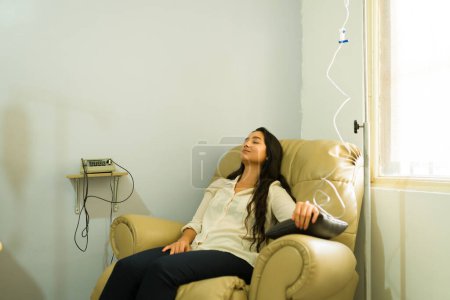 Glückliche attraktive Frau entspannt sich, während sie IV-Tropf und Vitaminmineraltherapie für eine bessere Gesundheit mit einem Myers-Cocktail bekommt