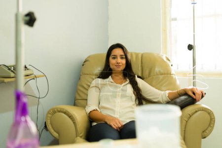 Beautiful hispanic woman at the alternative medicine clinic getting IV drip and vitamin therapy with myers cocktail for better health