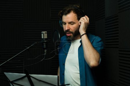 Foto de Un hombre enfocado grabando voz en off con auriculares en un estudio insonorizado - Imagen libre de derechos