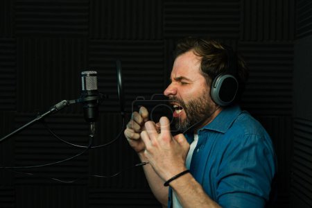 Foto de Actor de voz caucásico gritando y retratando a un personaje enojado durante una grabación de voz - Imagen libre de derechos