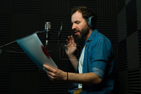 Male voice actor with headphones performs in a soundproof recording studio