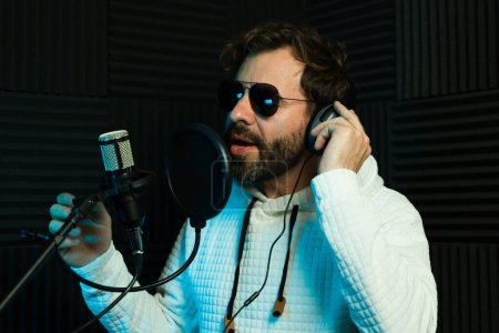 Photo for Famouse lead singer wearing sunglasses and recording a song in a soundproof studio - Royalty Free Image