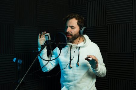 Konzentrierter Mann singt in professionellem Studio-Setting in ein Mikrofon und trägt Kopfhörer